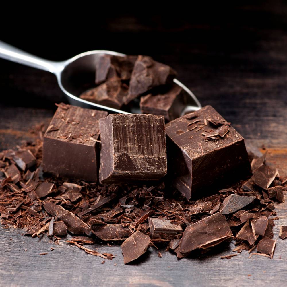 Dark chocolate in a metal scoop and on a table